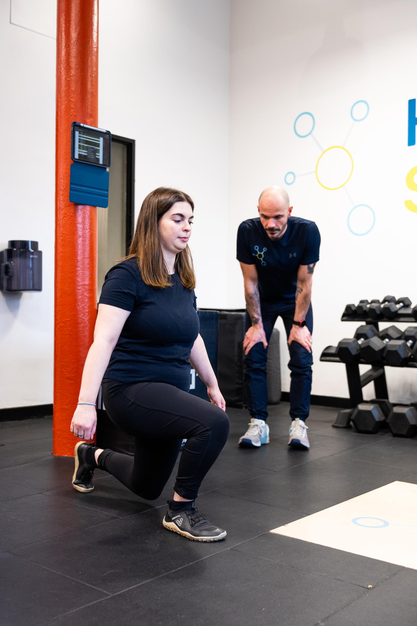 KA3_2765 Specialist conducting a biomechanical movement screening to assess knee stability for a personal training Edinburgh client.