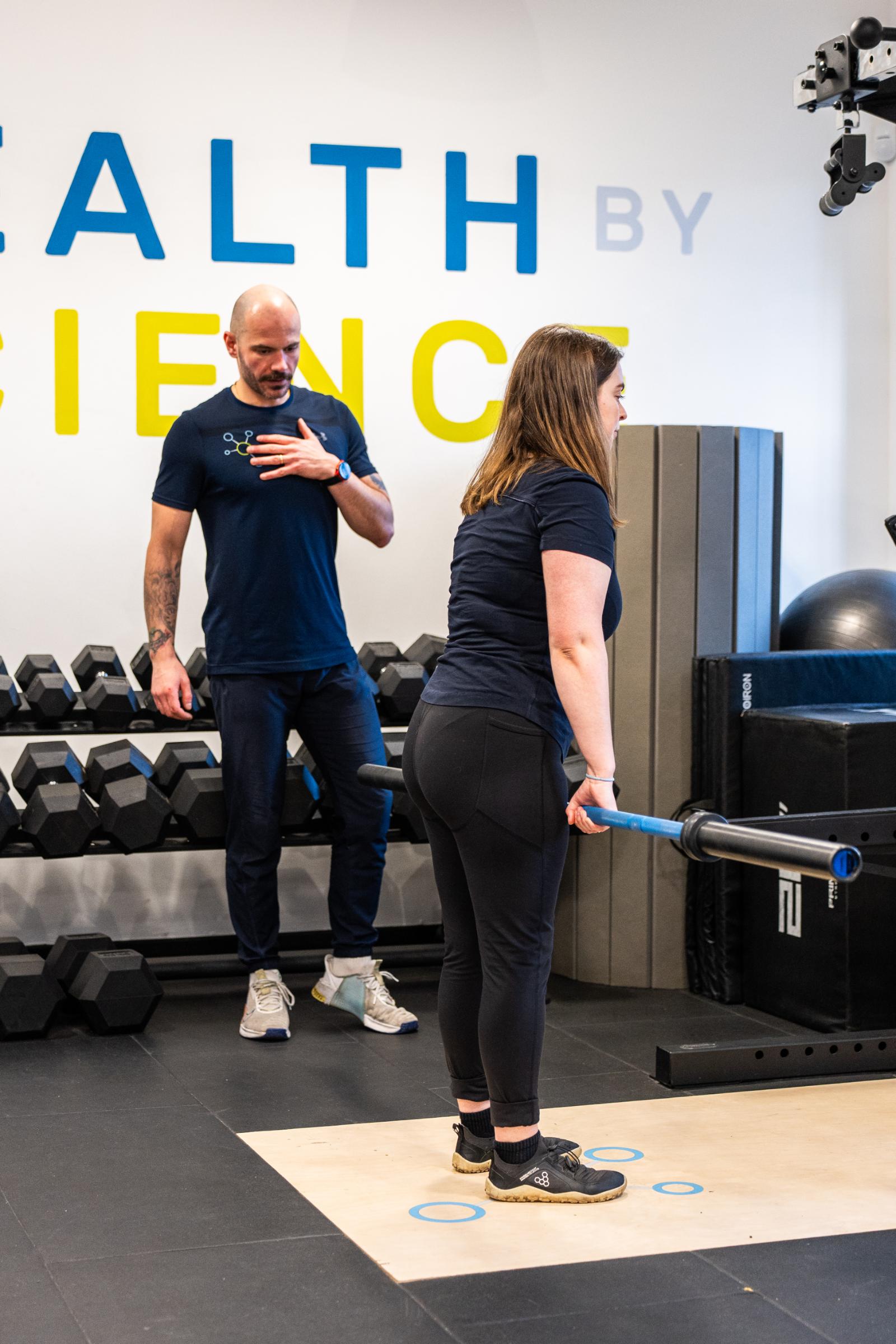 KA3_2885 Specialist observing barbell deadlift technique to ensure safe lumbar mechanics for sports physiotherapy Edinburgh patients.