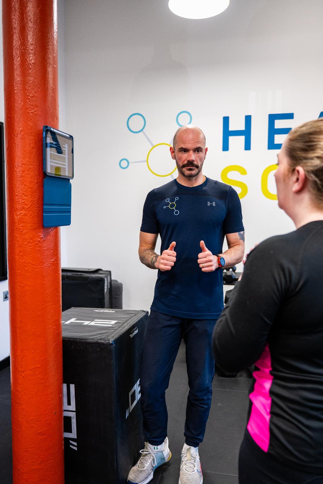 KA3_2979 Professional Health by Science coach providing clinical feedback and encouragement during a personal training session.