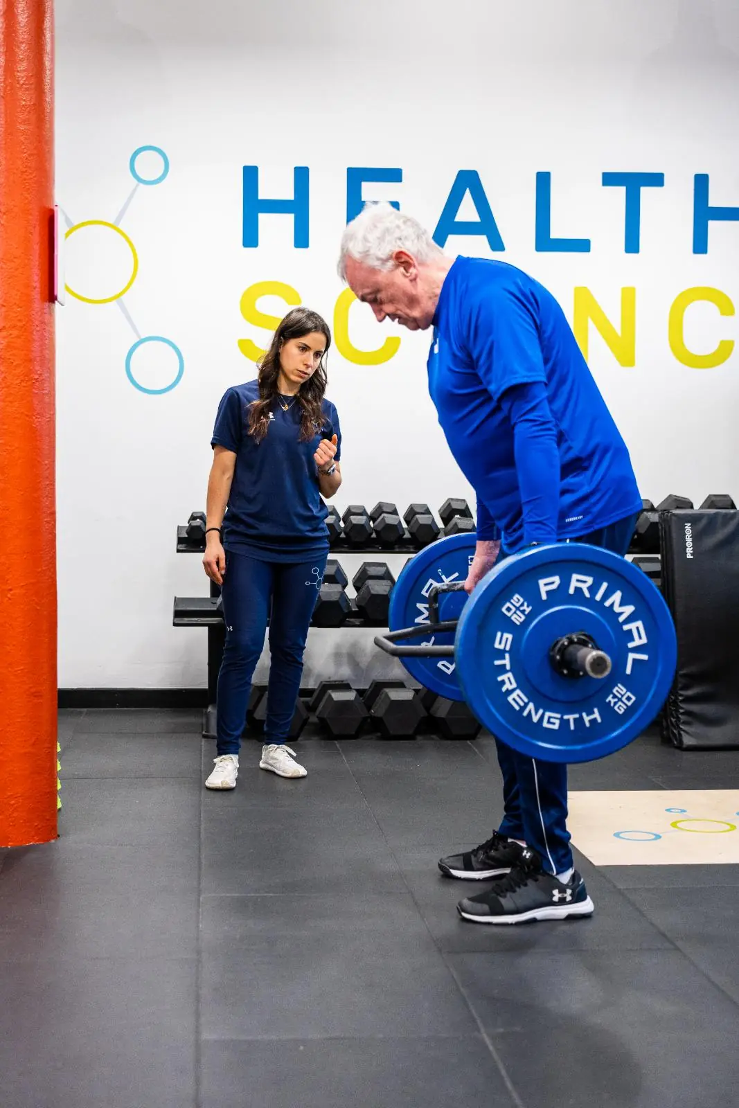 KA3_3186 Health by Science coach provide technical cues for a barbell hip hinge movement to support long-term injury prevention.