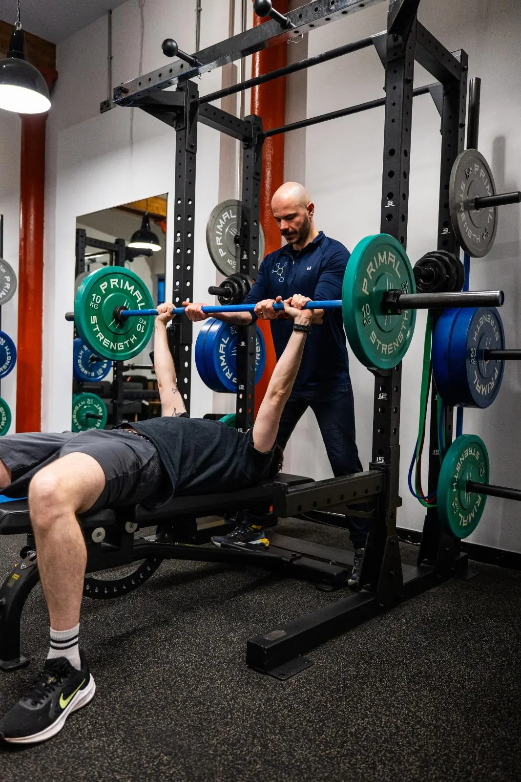 KA3_3518 Senior coach providing a safe spot and technical feedback for a barbell bench press during a personal training Edinburgh session.