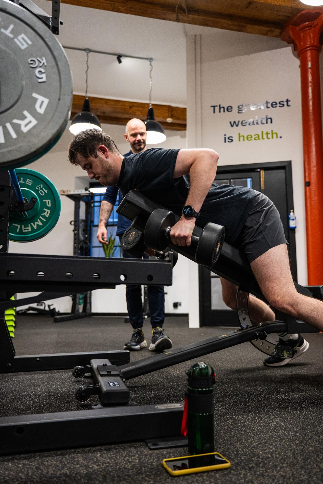 KA3_3534 Health by Science specialist providing clinical supervision for a dumbbell chest-supported row to improve postural stability and upper body strength.