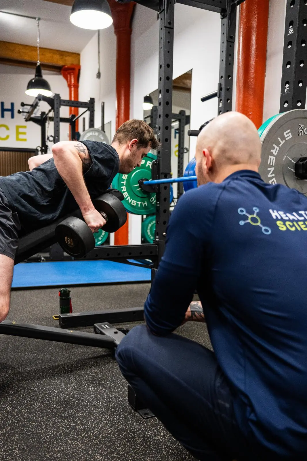 KA3_3613 Specialist providing clinical movement instruction for a chest-supported dumbbell row to improve postural health.