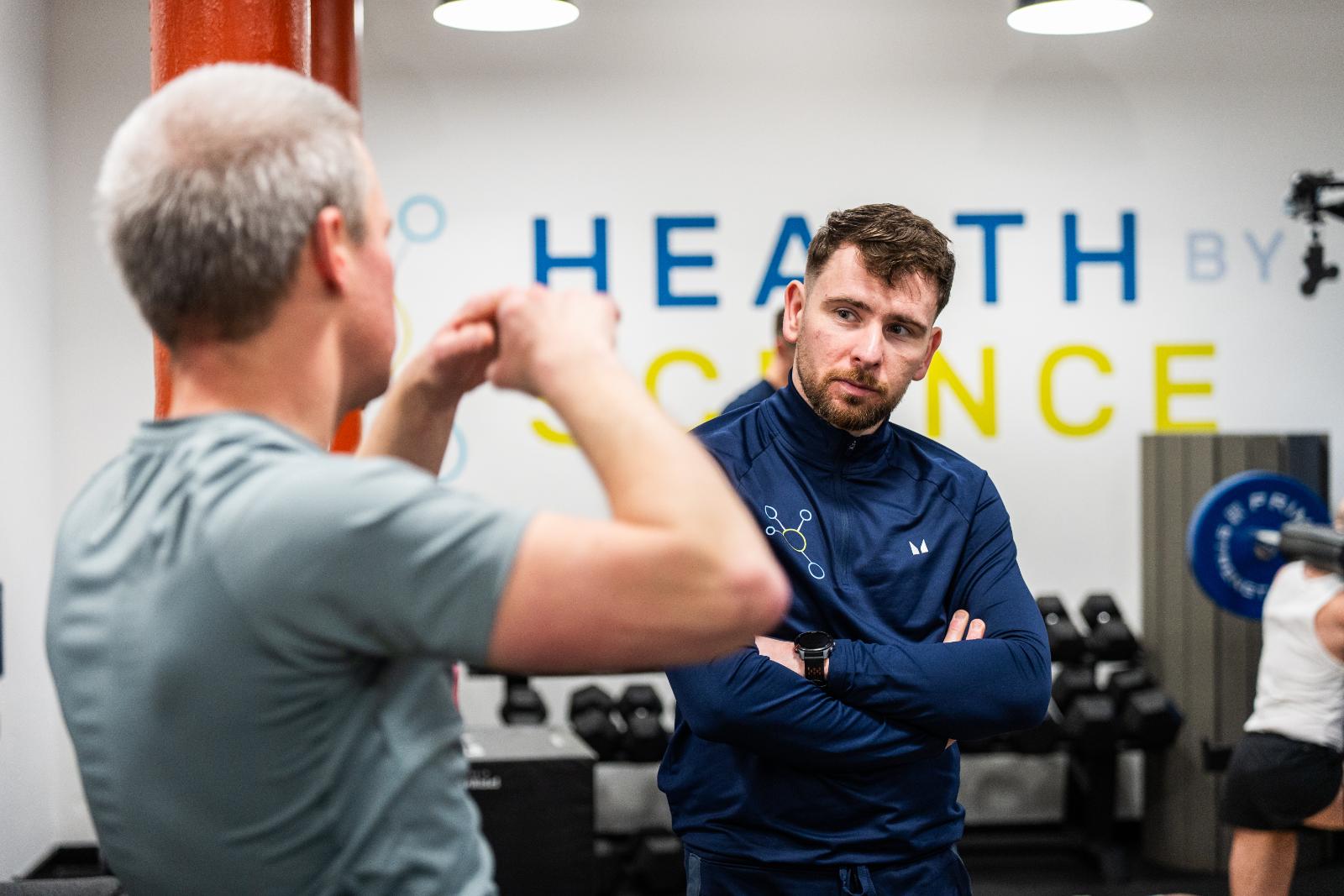 Clinical consultation between a practitioner and client to discuss evidence-based exercise progressions for injury recovery.