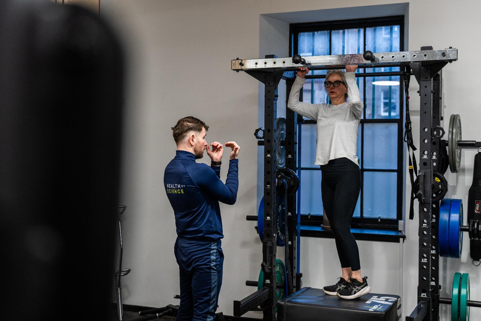 Health by Science specialist providing verbal cues and technical coaching for a vertical pulling exercise in our Leith lab.