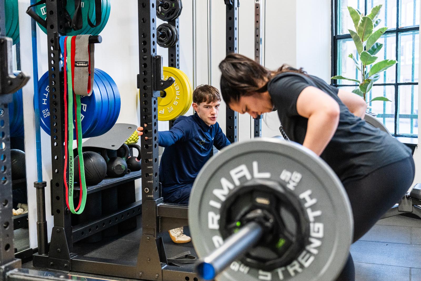 KA3_4104 Professional monitoring of a bent-over barbell row to ensure safe spinal alignment during a personal training Edinburgh session.