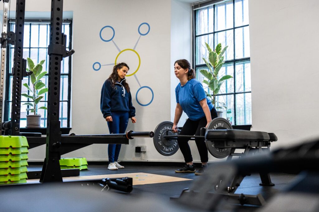 Personal trainer in Edinburgh at Health by Science coaching a woman through a barbell deadlift in the Leith studio