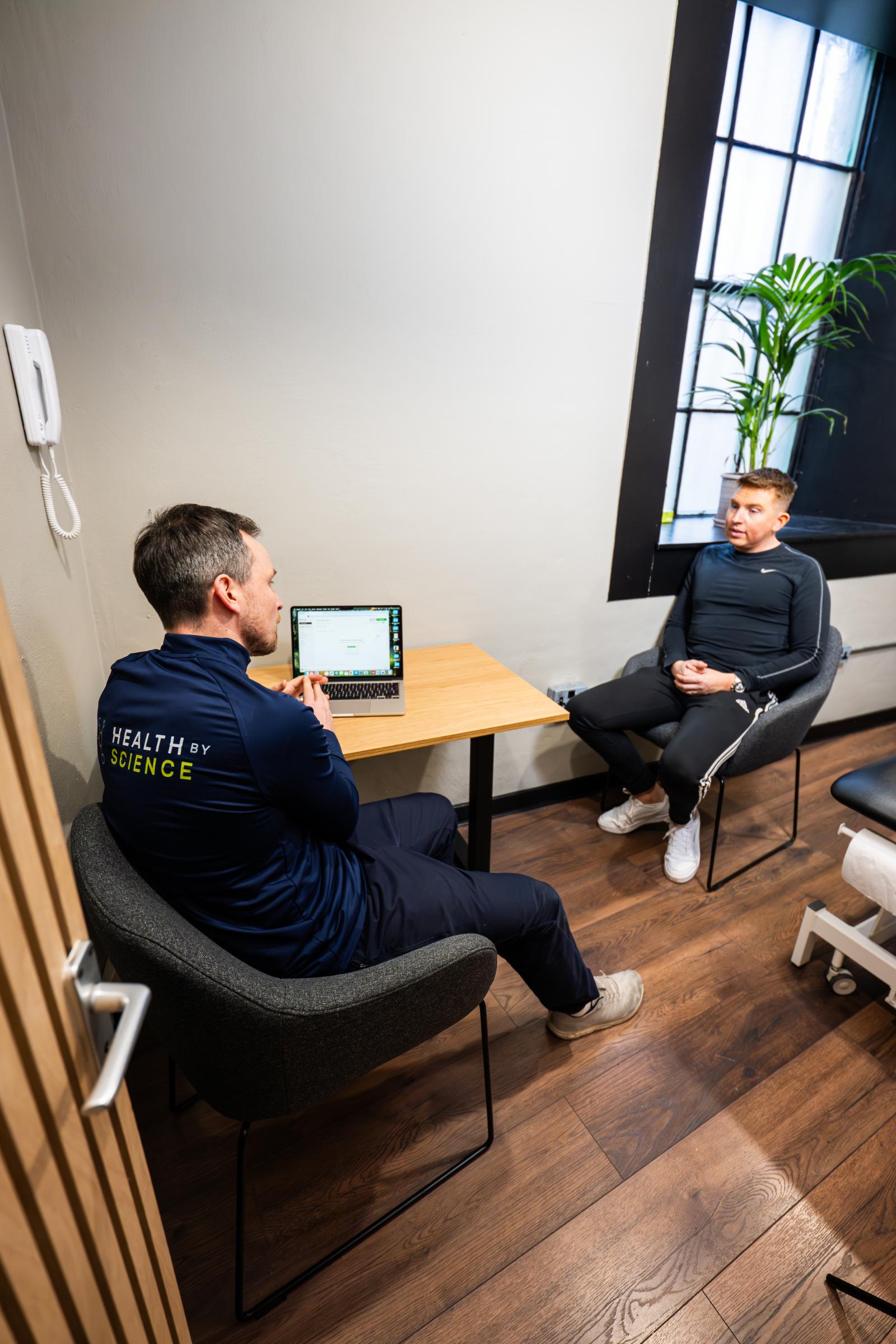 KA3_4602 Health by Science specialist using a laptop to track real-time clinical biometrics during a one-to-one patient session.