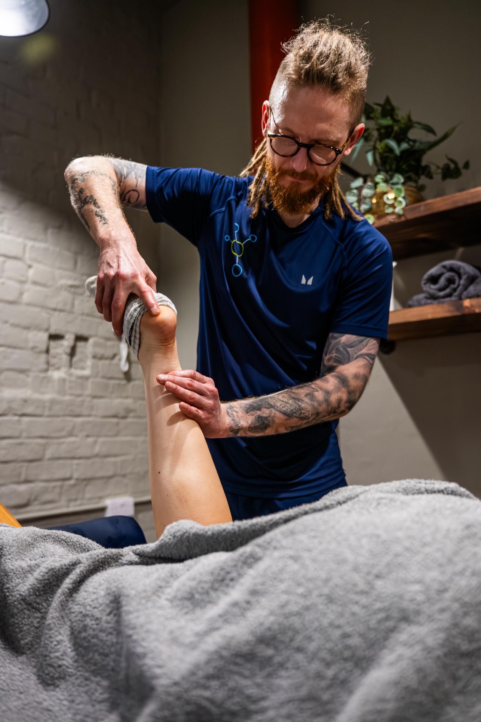 KA3_5778 Health by Science specialist conducting a clinical manual assessment of ankle joint range of motion on a treatment plinth.